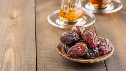 Dates with black tea on a wooden table. Traditional iftar food during Ramadan.