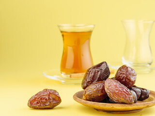 Dates with black tea on a yellow background. Traditional iftar food during Ramadan.