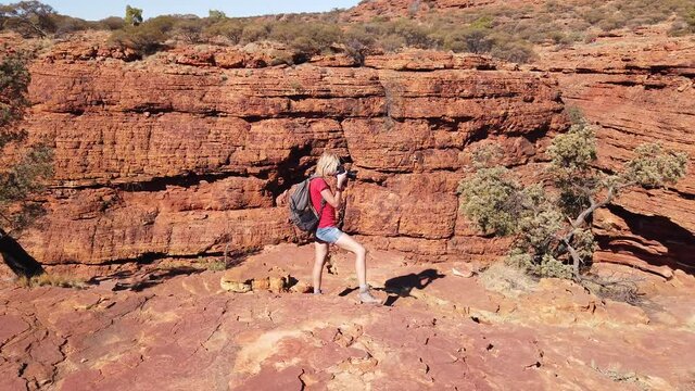 Travel photographer taking pictures of sandstone cliff in Kings Canyon Watarrka National Park. Central Australia travel discovery concept. Woman with professional camera in Northern Territory, Outback