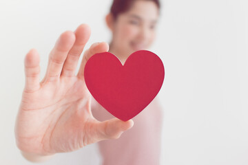 Woman in pink dress shows heart shape in the concept of love and valentine.