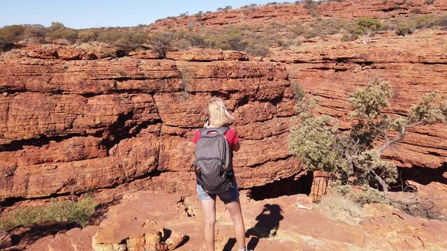 Woman with professional camera in Northern Territory, Outback. Photographer woman taking pictures of sandstone cliff in Kings Canyon Watarrka National Park. Central Australia travel.