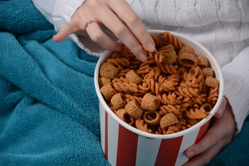 A bowl of Israeli Bissli wheat snacks with different flavors and shapes in girl's hands.
