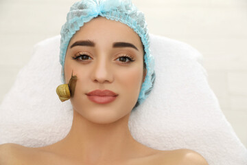 Young woman receiving snail facial massage in spa salon