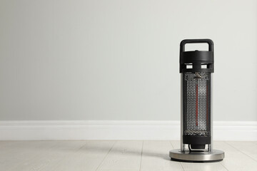 New modern electric heater on floor in room, space for text - obrazy, fototapety, plakaty