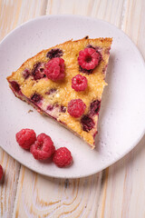 Sweet tasty pie slice with jellied and fresh raspberry fruits in plate, wooden table background, angle view