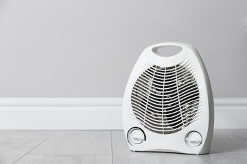 Modern electric fan heater on floor in room, space for text