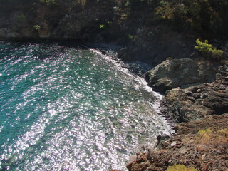 A dizzying view from the incredible height of a steep cliff on the rocky coast of the azure sea bay.