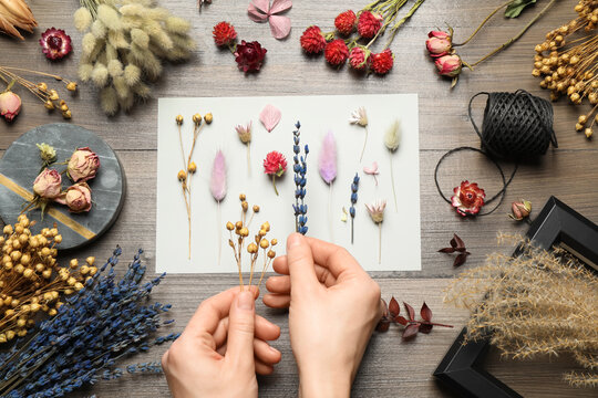 Woman Making Herbarium Of Dry Flowers At Wooden Table, Closeup