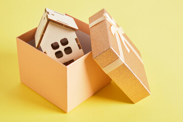 Obraz premium small house model in a gift box on a yellow background