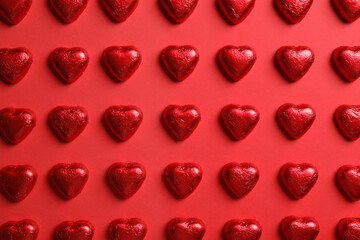 Naklejka na ściany i meble Tasty chocolate heart shaped candies on red background, flat lay