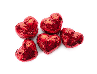 Heart shaped chocolate candies in red foil on white background, top view