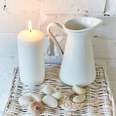 Still Life with Burning Candle and Snowdrops in White, with white brick wall background and white stones