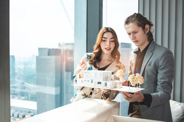 Couple of young designers working at modern office, two coworkers discussing fun project over a laptop, little team of businesspeople smiling and looking together at computer, students at library