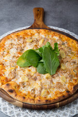 Pizza with chicken meat, onion, baby corn and rocket leaves on wooden pizza plate 