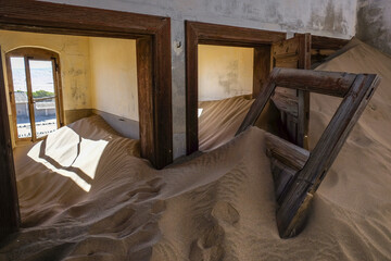 Room full of sand with colored door in the ghost town of Kolmanskop, Namibia