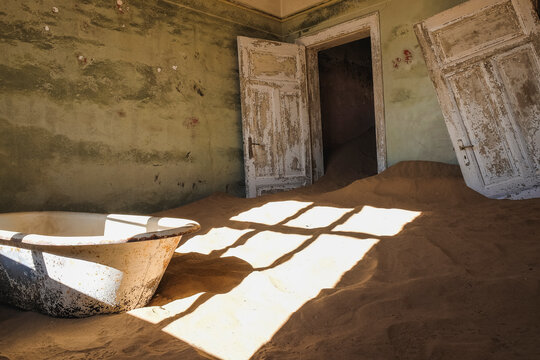 Room full of sand with white door in the ghost town of Kolmanskop, Namibia
