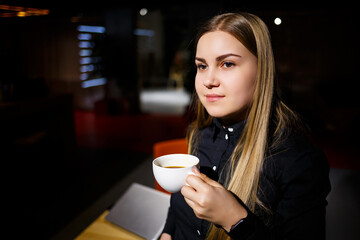 Normal working day of modern woman businessman. Beautiful young woman holding a cup of coffee while sitting at her workplace