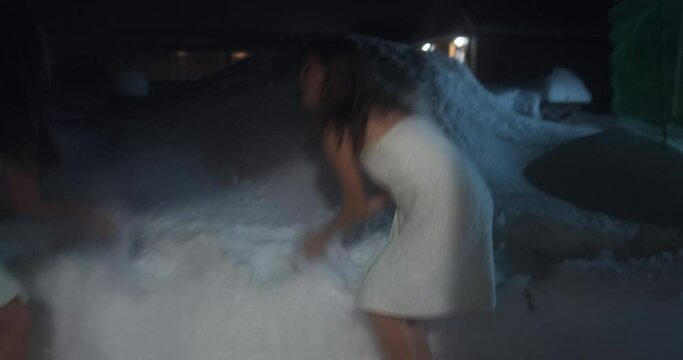 Women play with snow after sauna. Two young women cool down with snow after hot sauna and quickly run back inside