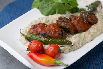 Meatballs on eggplant puree with pepper and tomato