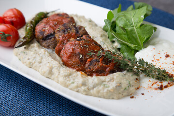 Meatballs on eggplant puree with pepper and tomato