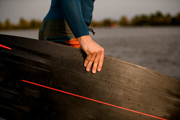 Close-up of man's hand holding black wakeboarding board.