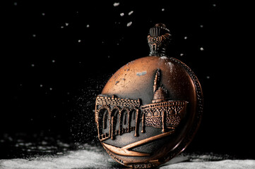 Vintage watch on a black background with falling snow. An idea for Christmas themes, historical...