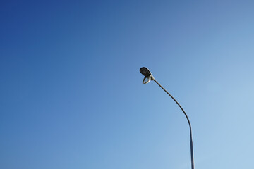 A cover of electric lamp is open and hanging.  It's out of order.  It represents the maintenance,  fixing and repairing the object.  Blue sky in the background.  