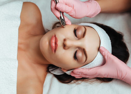 beautician in pink gloves doing microdermabrasion