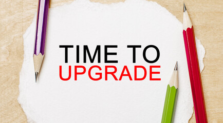 Text Time to upgrade on a white notepad with pencils on a wooden background. Business concept
