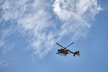 Fototapeta na wymiar A Police helicopter flying in the cloudy blue sky over Madrid