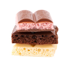 Mix of porous chocolate pieces isolated on white background. Black, white and pink aerated chocolate.