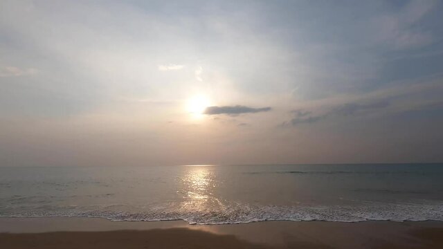Timelapse of beautiful sunset sky and beach in summer season. clouds moving toward sun, patten sea waves dancing on sandy beach. sparkling sunlight on water surface. pink pastel seascapes background.
