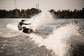 young healthy man rides on wakeboard and falling into the splashing water