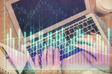 Double exposure of man's hands typing over computer keyboard and forex graph hologram drawing. Top view. Financial markets concept.