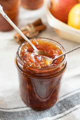 Homemade apple jam marmalade with cloves and cinnamon from organic apples in a transparent glass jar with two vintage retro spoon. Homemade autumn jam preserves.