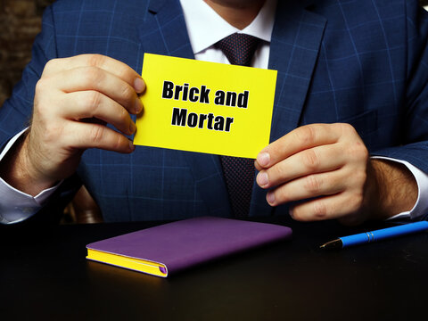 Business Concept Meaning Brick And Mortar With Phrase On Yellow Business Card.