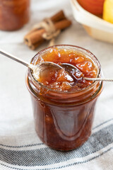 Homemade apple jam marmalade with cloves and cinnamon from organic apples in a transparent glass jar with two vintage retro spoon. Homemade autumn jam preserves.