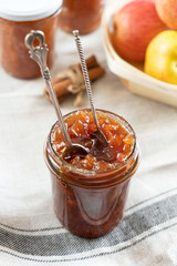 Homemade apple jam marmalade with cloves and cinnamon from organic apples in a transparent glass jar with two vintage retro spoon. Homemade autumn jam preserves.