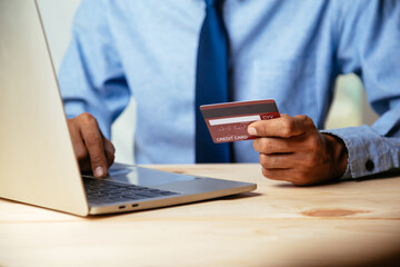 Man holding credit card and using laptop computer. Online shopping concept.