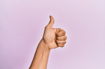 Arm and hand of caucasian young man over pink isolated background doing successful approval gesture with thumbs up, validation and positive symbol