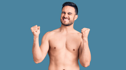 Fototapeta premium Young handsome man wearing swimwear very happy and excited doing winner gesture with arms raised, smiling and screaming for success. celebration concept.