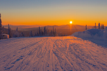 The setting sun illuminates the ski run in winter