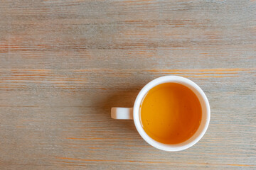 A white cup of green tea stands on a light table. Top view, copy space