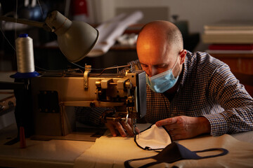man working with sewing machine doing homemade face mask for preventing and stop corona virus spreading