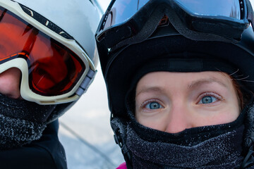 portrait woman and man at a ski slope. It is cold. The woman's eyelashes are covered with frost