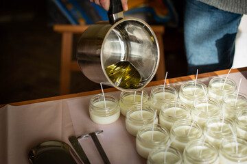 Woman pouring melted wax into amber candles container. Ecological and vegan business. Soya wax candle accessories. Handmade with love. Remote work, online shop, workplace