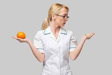 nutritionist doctor healthy lifestyle concept - holding fresh organic orange fruit and vitamin...
