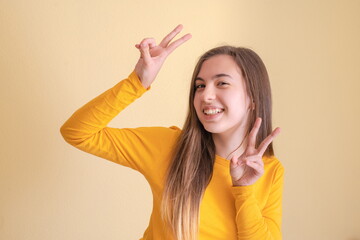Young woman making the path sign on yellow background