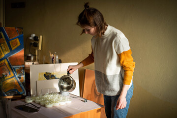 Woman pouring melted wax into amber candles container. Ecological and vegan business. Soya wax candle accessories. Handmade with love. Remote work, online shop, workplace