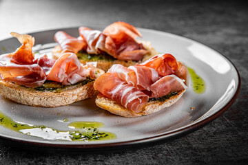 Bruschetta with prosciutto and pesto sauce on plate